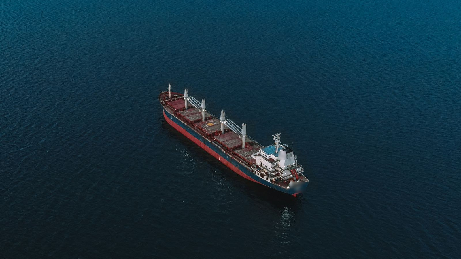 Aerial view of a cargo ship sailing across deep blue open sea